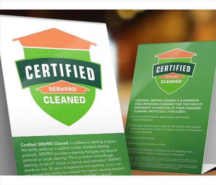 Table tent signs describing the Certified: SERVPRO Cleaned program on top of a wooden table.